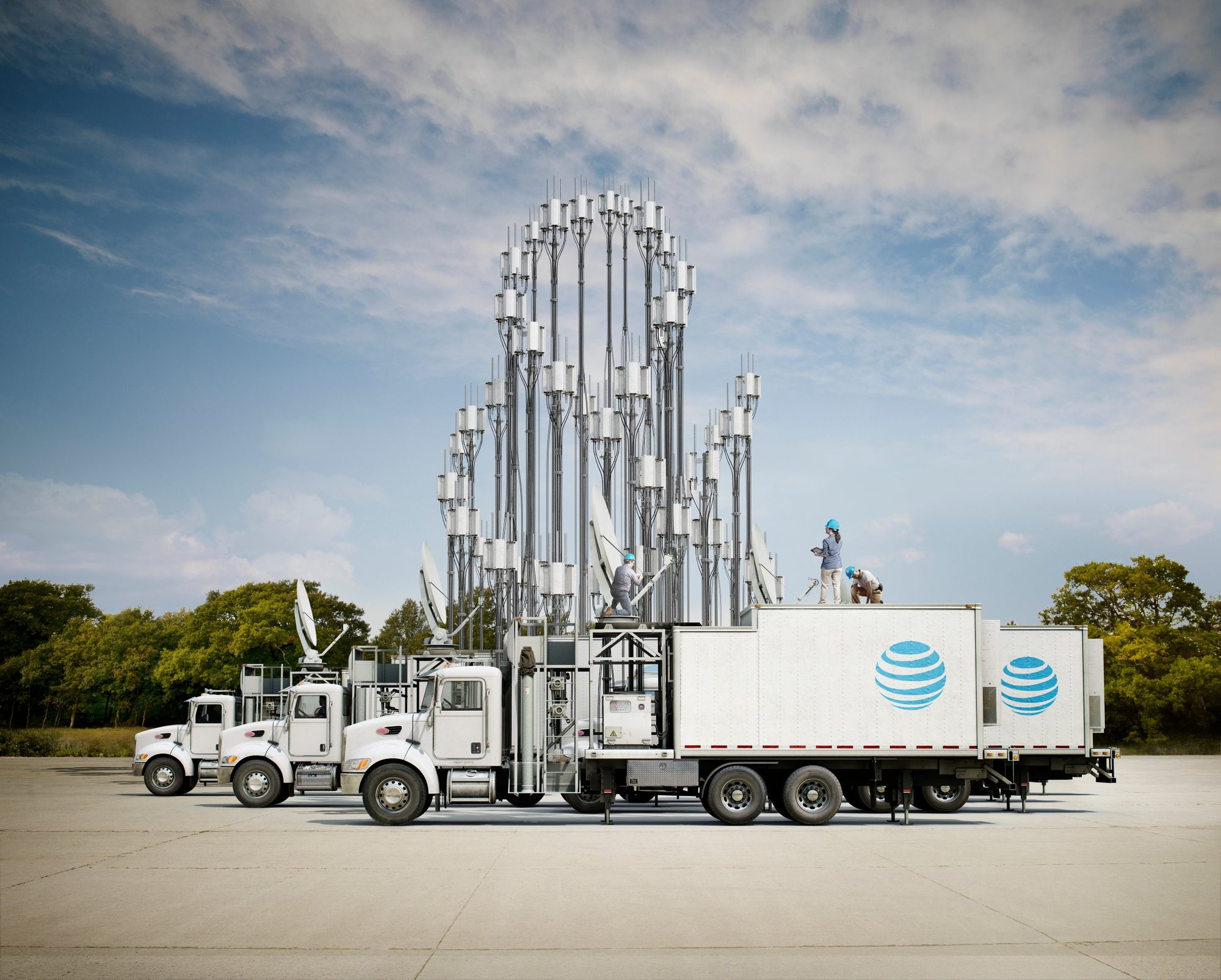 AT&T Ampersand: three CGI mobile cell trucks raising a forest of antenna masts, with engineers on the roof